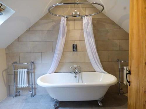 a white bath tub in a bathroom with a staircase at Fire Brigade Barn in Tissington