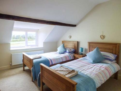 a bedroom with two beds and a window at 2 Ysgubor Gerrig in Trefriw