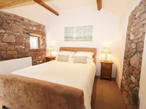 Faraway Cottage في Kirklinton: غرفة نوم بسرير كبير وجدار حجري