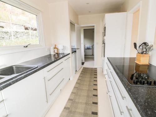 a kitchen with white cabinets and a sink and a window at Middle Hivron in Bleddfa