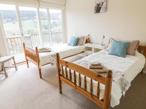 a bedroom with two beds and a large window at Middle Hivron in Bleddfa