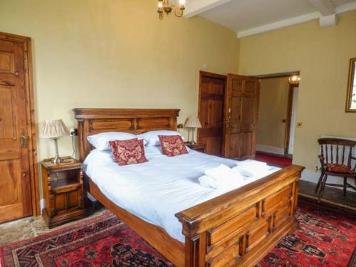 a bedroom with a large wooden bed with two red pillows at Walcot Farm in North Lydbury