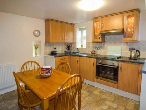 a kitchen with a wooden table and wooden cabinets at Post Box Cottage in Staithes