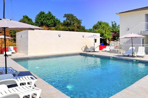 une piscine avec des chaises blanches et des parasols dans l'établissement Apartment in Corsica near Sandy Beach, à Santa-Lucia-di-Moriani