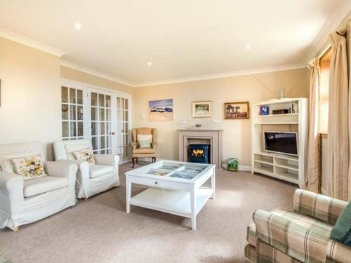a living room with white furniture and a fireplace at Little Laight in Cairnryan