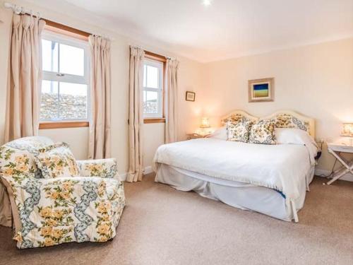 a bedroom with a bed and a chair and a window at Little Laight in Cairnryan