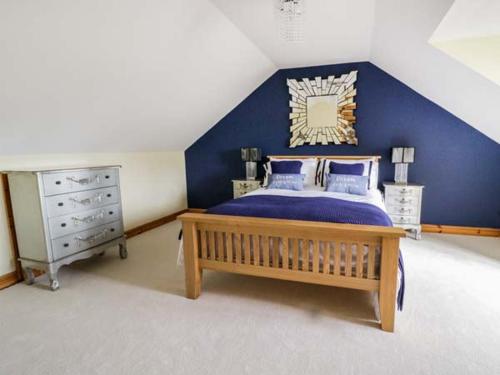1 dormitorio con cama y pared azul en 1 The Old Smithy, en Cemaes