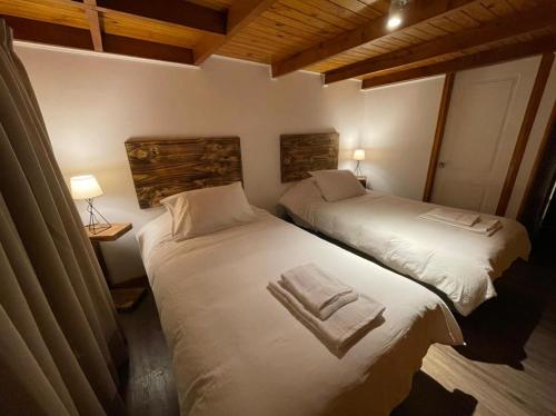 two beds in a hotel room with towels on them at HOTEL VOLKANICO in Curacautín