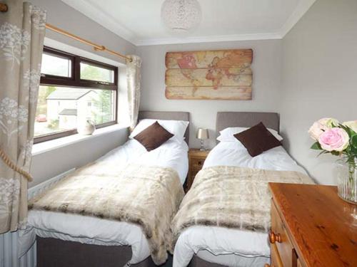 a bedroom with two beds and a window at Woods View Cottage in Tansley