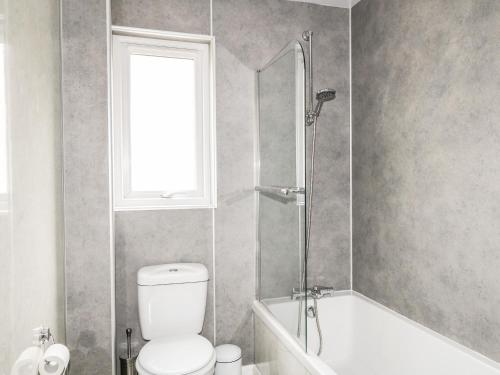 a bathroom with a toilet and a tub and a window at 79 Corrour Road in Aviemore