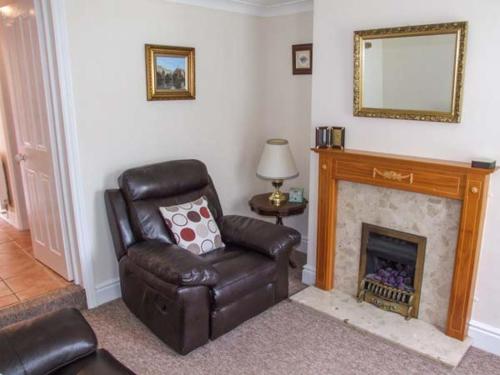 a living room with a chair and a fireplace at 11 Victoria Cottages in Stratford-upon-Avon