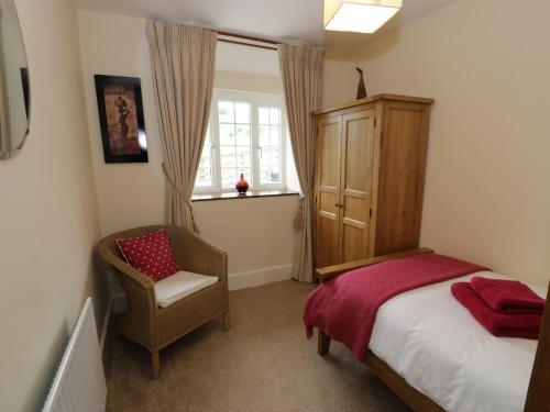 a bedroom with a bed and a chair and a window at Hafan in Llanerfyl