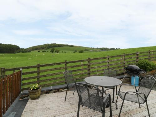 a patio with a table and chairs and a fence at Hafan in Llanerfyl