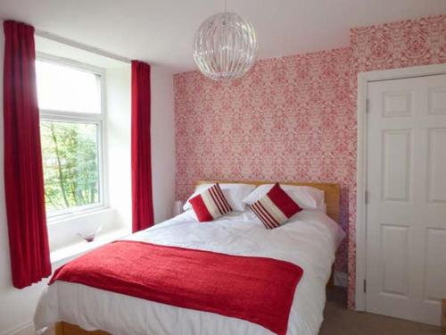 a bedroom with a bed with red curtains and a window at Crooklands House 3 in Crooklands