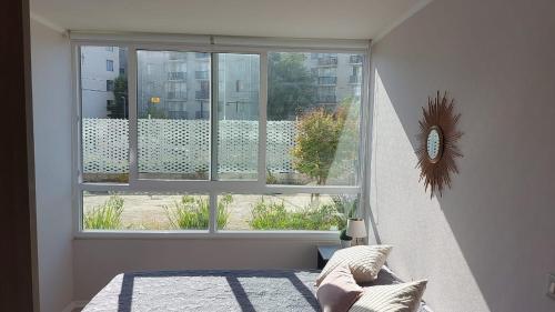 a bedroom with a window with a view of a building at Hermoso departamento muy cerca del centro, playas, malls, hipermercado, hospital y clínicas in La Serena