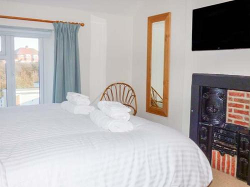 a bedroom with a white bed with pillows and a fireplace at Smugglers' Cottage in Marske-by-the-Sea