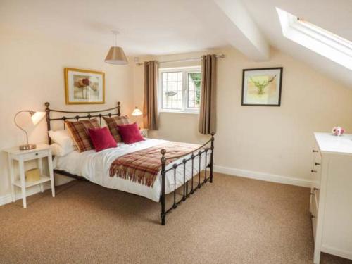 a bedroom with a bed with red pillows and a window at Poacher's Rest in Great Rowsley