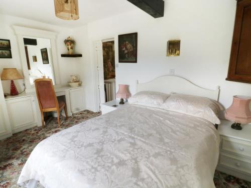 a bedroom with a white bed and a desk at Sally's Cottage in Carleton