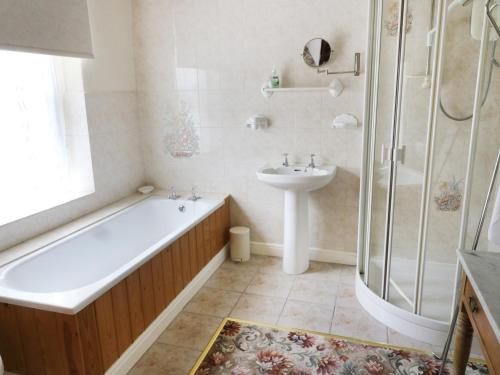 a bathroom with a tub and a sink and a shower at Sally's Cottage in Carleton