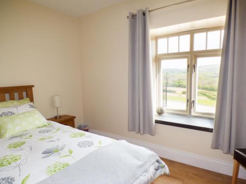 a bedroom with a bed and a window at Llaethdy - The Dairy in Newchapel