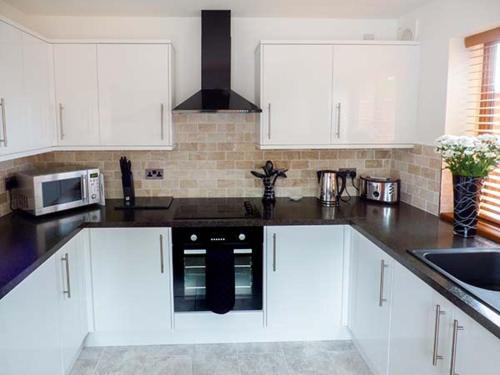 a kitchen with white cabinets and a black appliance at 1 The Potteries in Eryholme