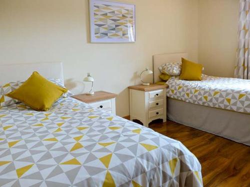 a bedroom with two beds with yellow and white at 1 The Potteries in Eryholme