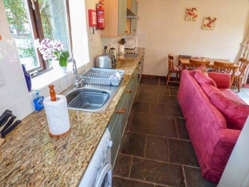 eine Küche mit einem Waschbecken und einem lila Sofa in der Unterkunft The Old Parlour in Winford