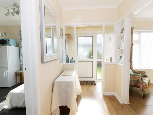 a small white room with a table and windows at Bungalow in Fishguard