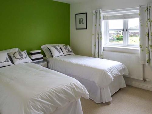 a green bedroom with two beds and a window at Pinnacle View in Cowling