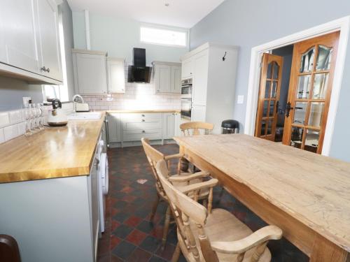 a kitchen with white cabinets and a wooden counter top at No 1 Church Cottages in Llanelli