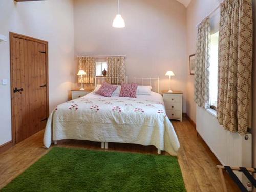 a bedroom with a large bed and a green rug at Y Wennol in Holyhead