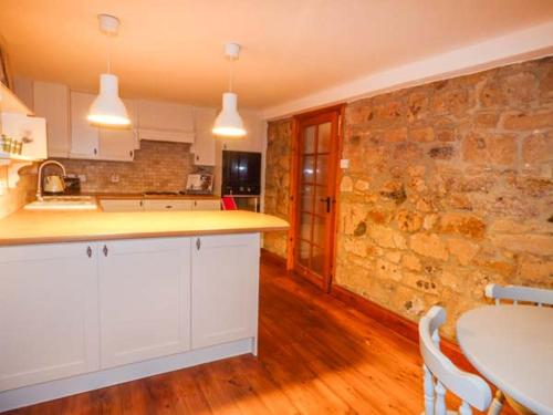 a kitchen with a table and a stone wall at Edendale in Longframlington