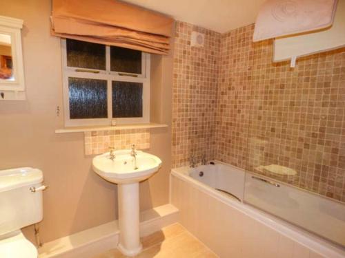 een badkamer met een wastafel, een toilet en een bad bij Edendale in Longframlington