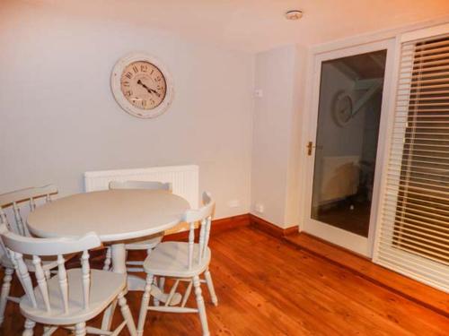 a dining room with a table and chairs and a clock on the wall at Edendale in Longframlington