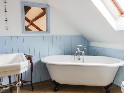 a white bath tub in a blue bathroom with a sink at Cottage Val in Fylingdales