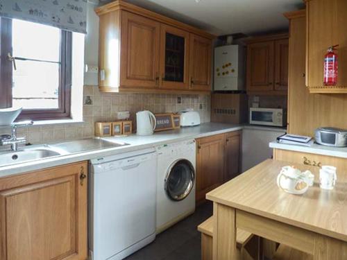 a kitchen with a washing machine and a sink at Fairwater Mill Cottage in Kingsteignton