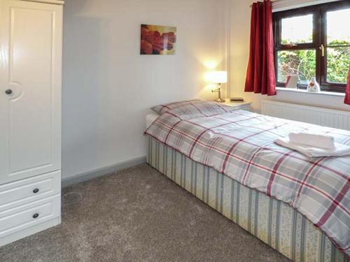 a small bedroom with a bed and a window at Fairwater Mill Cottage in Kingsteignton