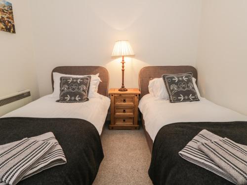 two beds in a room with a lamp on a night stand at Station View in Pickering