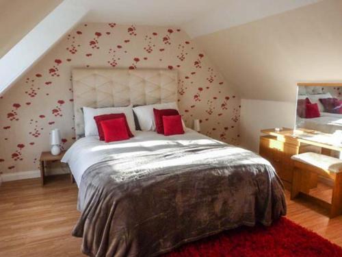 a bedroom with a large bed with red pillows at Coastal Cottage in Inverallochy