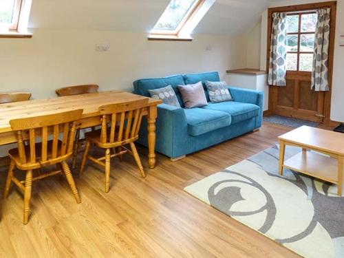 a living room with a blue couch and a table at Lakefield Apartment in Bearnock