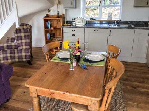 a wooden table with two plates and flowers on it at Gwdihw in Ifton Heath