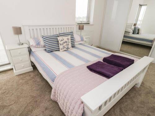 a bedroom with a large bed with purple sheets and pillows at 3 Marina View in Pwllheli