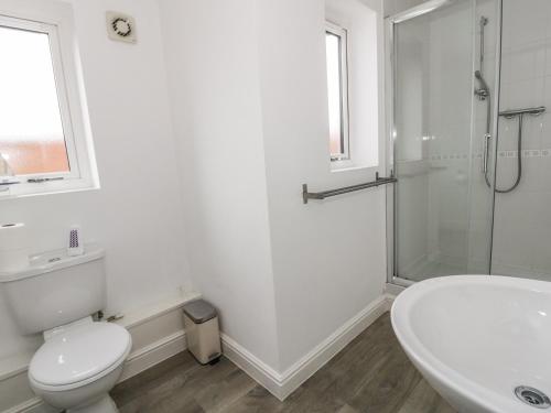 a white bathroom with a toilet and a shower at 3 Marina View in Pwllheli