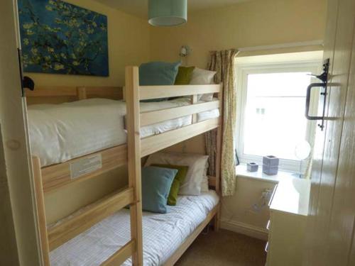 a bedroom with two bunk beds and a window at Fells Cottage in Sedbergh