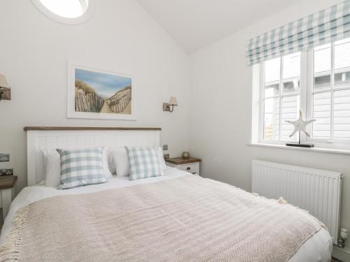 a white bedroom with a bed and a window at Beach Walk in Reighton