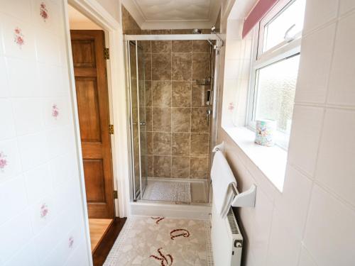 a walk in shower in a bathroom with a window at The Annex at 60 Rectory Lane in Poringland