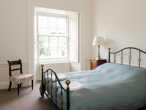 a bedroom with a bed and a window and a chair at Housekeeper's Rooms in Pathhead