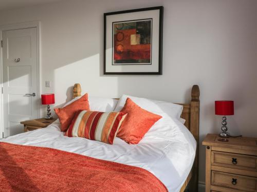 a white bed with orange pillows and a picture on the wall at Fistral Breeze in Newquay