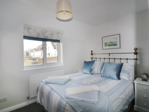 a bedroom with a bed with blue pillows and a window at Gull Cottage in Padstow