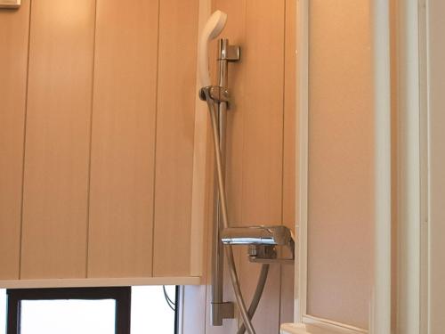 a shower with a hose hooked up to a cabinet at Guest Cafe Kuchikumano in Kamitondacho